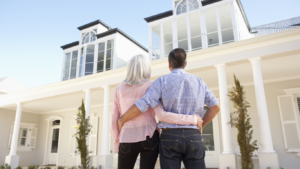 A woman and a man embrace each other in front of the house they just sold