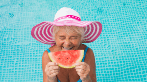 A woman in a pool holds up a slice of watermelon like it's a big smile