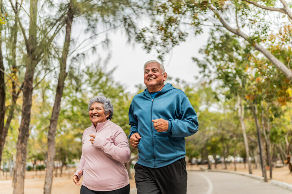 A senior woman and a senior man running in the forest