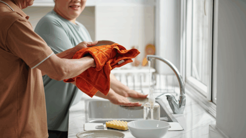 Close up of two seniors cleaning dishes together
