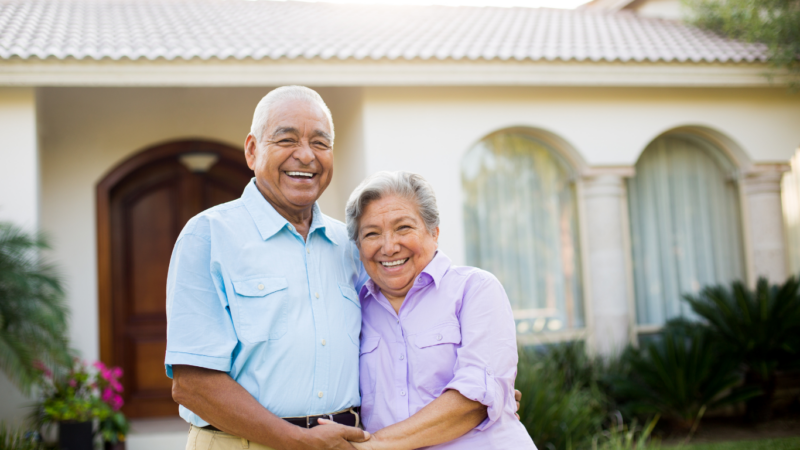 Senior couple standing in front of home