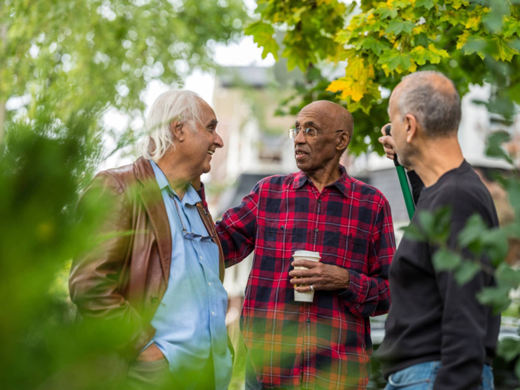 A group of senior men talk while standing outdoors