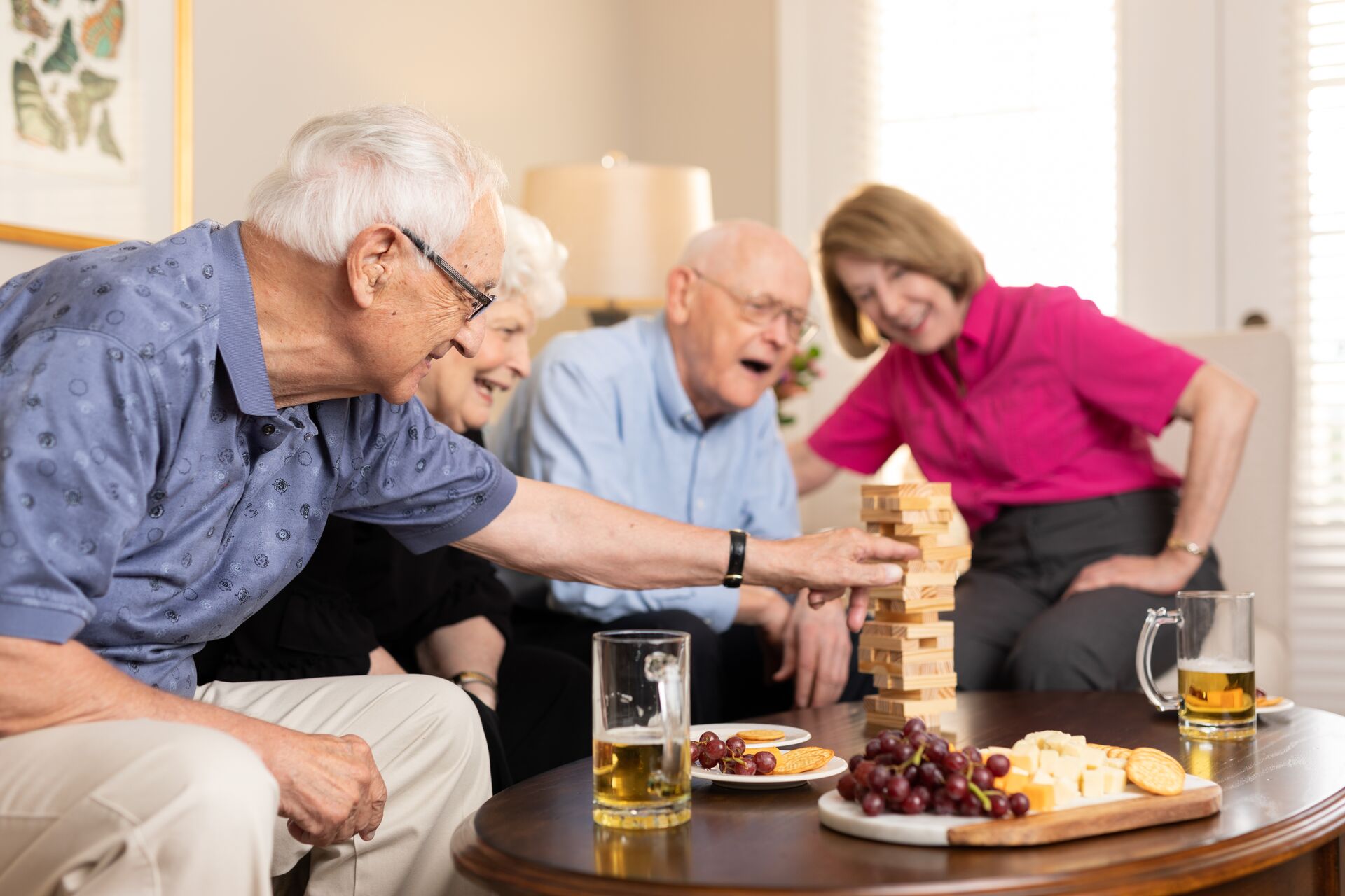 Senior residents playing jenga and enjoying beers in a senior living apartment.